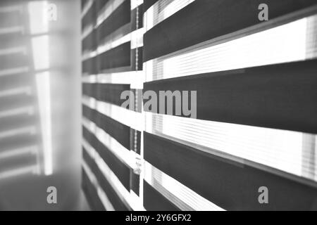 Sun shining through window roller blinds throwing shadows on the wall. Atmospheric mood. Selective focus Stock Photo