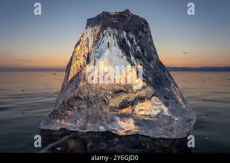 Sunset on frozen Lake Baikal landscape, sunlight is refracted in piece of ice Stock Photo