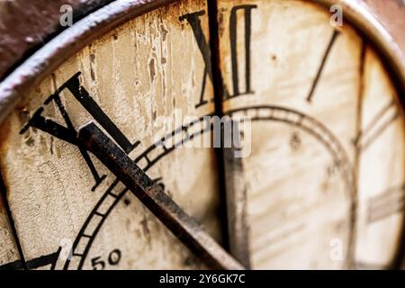 Old vintage and retro analogue clock displaying five minutes to twelve. Worn-out and grunge style with wooden background Stock Photo