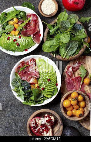 Food, Low carbs bowl. Fresh salad with green spinach, rucola, avocado an ham serrano in white bowl, gray background, top view Stock Photo