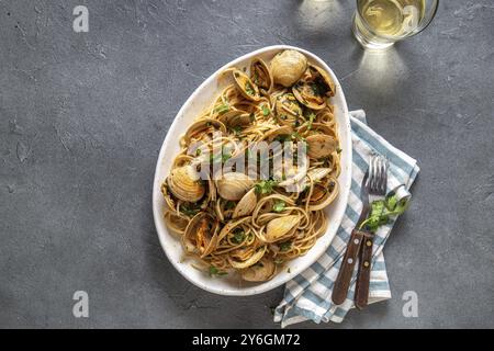 Food, Food, Seafood Pasta. ITALIAN SPAGHETTI ALLE VONGOLE. Clams spaghetti on white plate with white wine, gray background. Top view Stock Photo