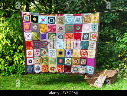 Handmade vintage colorful crochet granny square hanging on the string outdoor. Knitting in the style of patchwork. Hobby concept. Copy space. Stock Photo