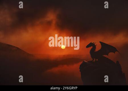 Mountain landscape with dragon winged silhouette sitting on the rock. Dramatic sunset in clouds background Stock Photo
