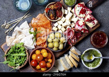 Food, Food, Antipasto. Wine set appetizer. Ham serrano, smoked salmon, dried and fresh tomatoes olive cheese, wine on board. Top view, gray cncrete ba Stock Photo