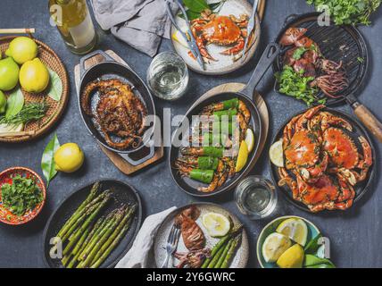 Food, Food, Set table with seafood dishes, cooked crabs, tiger shrimps, grilled octopus and squids on cast iron grilled pans and plates, White wine. T Stock Photo