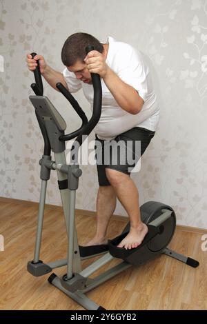 Overweight man exercising on trainer ellipsoid Stock Photo