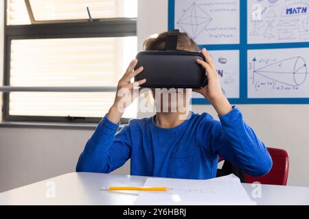Using VR headset, boy exploring virtual reality in school classroom Stock Photo