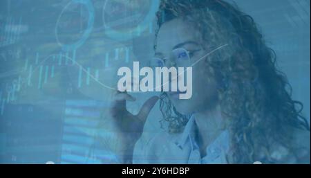 Image of diagrams and data processing over biracial businesswoman holding glasses Stock Photo