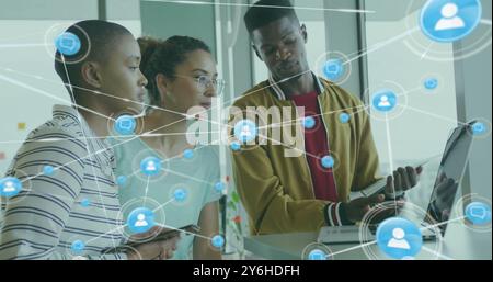 Image of network of connections with people icons over diverse business people in office Stock Photo