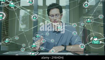 Image of network of connections with people icons over caucasian businessman in office Stock Photo