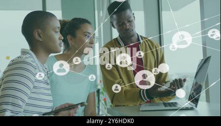 Image of network of connections with people icons over diverse business people in office Stock Photo