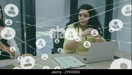 Image of network of connections with people icons over diverse business people in office Stock Photo