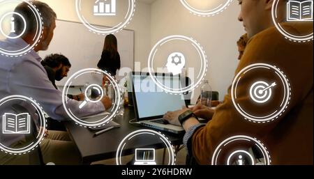 Image of icons over diverse collleagues having meeting in office Stock Photo