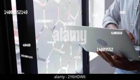 Image of data processing over african american businessman using laptop in office Stock Photo