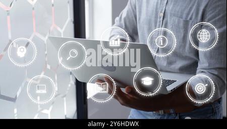 Image of icons over african american businessman using laptop in office Stock Photo