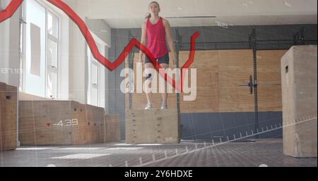 Red line graph image over woman standing on wooden box in gym Stock Photo