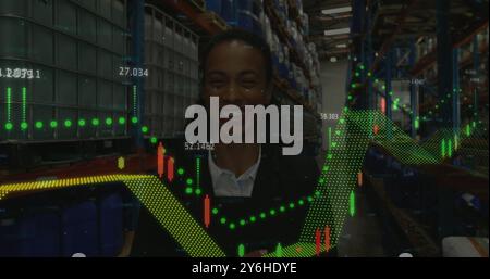 Image of financial data processing over african american businesswoman in warehouse Stock Photo