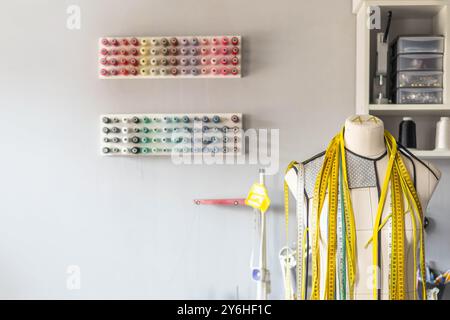 Sewing workshop. Mannequin for trying on clothes. Multi-colored threads for sewing. Stock Photo
