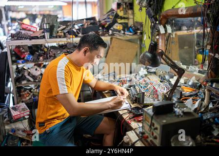 portrait of an electrical repairman sitting writing a list of electronic equipment Stock Photo