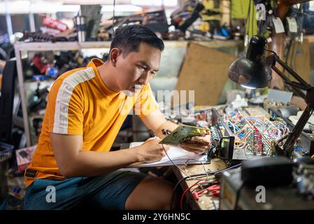 repairman looking at a circuit while working at a workbench Stock Photo