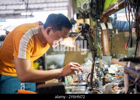 technician working on testing electronics using a screwdriver under the light Stock Photo