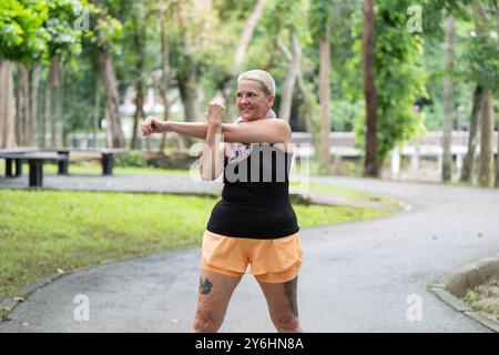 Senior Woman Performing Stretching Exercises in Park for Flexibility and Wellness Stock Photo