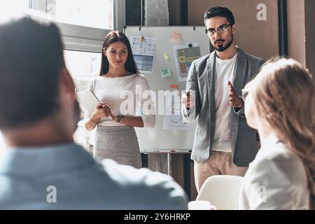 Developing new strategy. Two young colleagues conducting presentation while working with their business team in the office Stock Photo