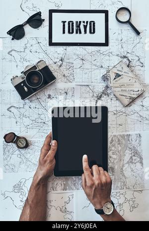 Tokyo. Close up top view of man using digital tablet in front of the map Stock Photo