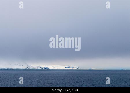 Low hanging clouds partially obscure the view on the mountains and glaciers lining the Gerlache strait along the Antarctic peninsula. Stock Photo