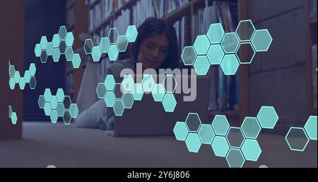 Image of element structure over happy caucasian female student using laptop in library Stock Photo