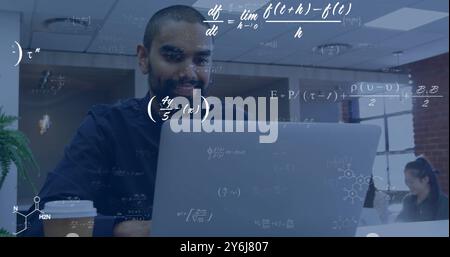 Image of equations at elements over happy biracial male student using laptop in classroom Stock Photo