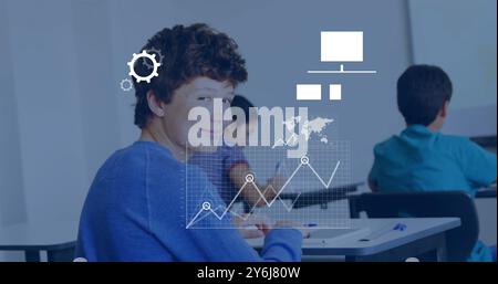 Image of data media icons processing over happy caucasian schoolboy smiling in classroom Stock Photo