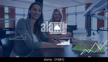 Image of data media icons processing over happy caucasian female colleagues at casual office Stock Photo
