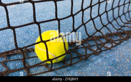 Ball in the shade of the net of a blue paddle tennis court. Stock Photo