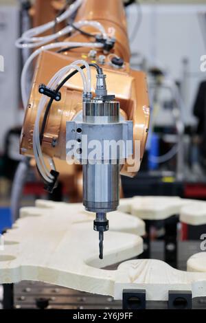 Robotic arm with milling end effector processes a wooden panel. Milling robotic cell. Six axis robots with cutting tools can handle cutting, drilling, Stock Photo
