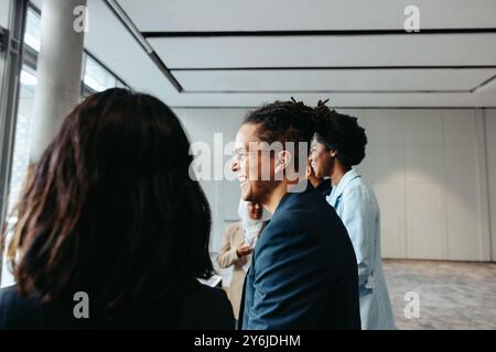 Young businessman with dreadlocks smiling while engaging with colleagues in a professional and happy work environment. Stock Photo