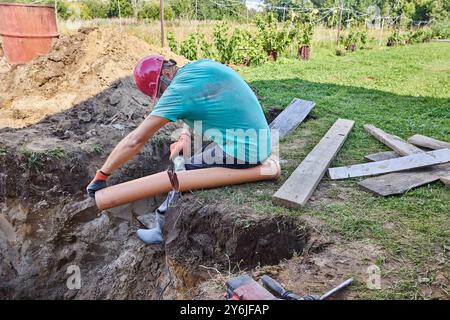 When installing septic tank, builder cuts off piece of plastic sewer pipe with an abrasive saw. Stock Photo