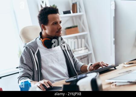 Computer hacker. Concentrated young man in casual clothing using computer while spending time at home Stock Photo