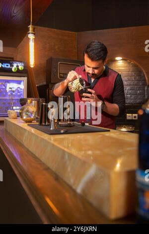 Barista preparing coffee in a Persian café with warm, inviting ambiance and traditional decor Stock Photo