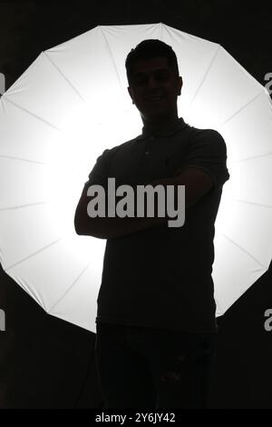 Silhouette of a man standing in front of a large studio light Stock Photo