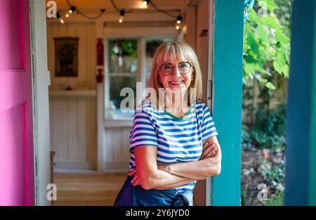 Portrait of a senior woman standing in front her wooden cottage Stock Photo