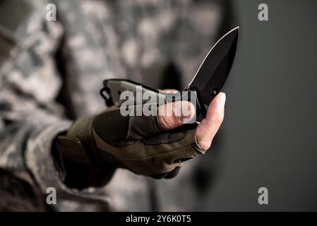 The man wearing tactical gloves using folding knife. Stock Photo