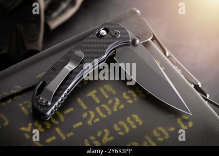 Folding knife with black blade and carbon fiber handle. Stock Photo