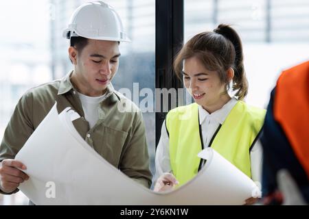 Architects Collaborating on Blueprint Plans at Construction Site with Safety Gear Stock Photo