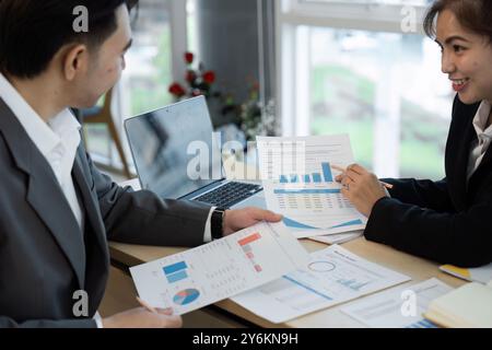 Business Meeting with Colleagues Analyzing Financial Reports and Graphs in a Modern Office Setting Stock Photo