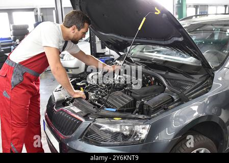 car mechanic in work clothes checks engine from a car in a workshop Stock Photo