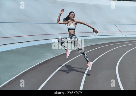 Determined to win. Full length of young woman in sports clothing jumping while exercising outdoors Stock Photo