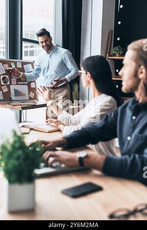 Taking important decision. Group of young business people using blackboard with adhesive notes while working in the office Stock Photo