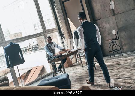 Perfect men. Two young fashionable men looking at each other while working in workshop Stock Photo
