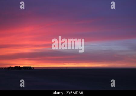 Evening atmosphere on the sea beach of saint peter-ording with pink play of colors in the cloudy evening sky Stock Photo